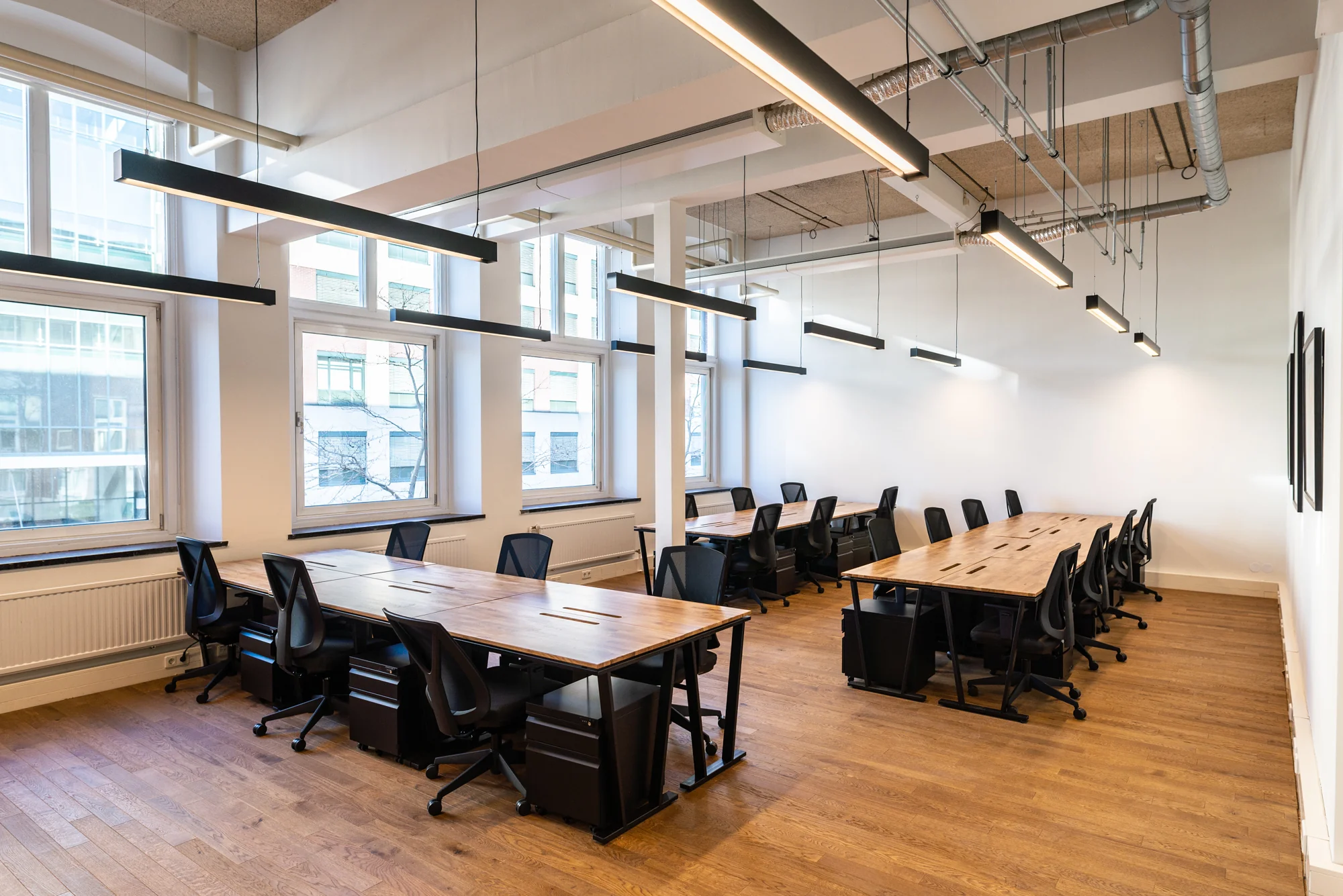 Modern ingerichte kantoorruimte bij Mindspace Utrecht met houten bureaus, zwarte bureaustoelen en grote ramen.