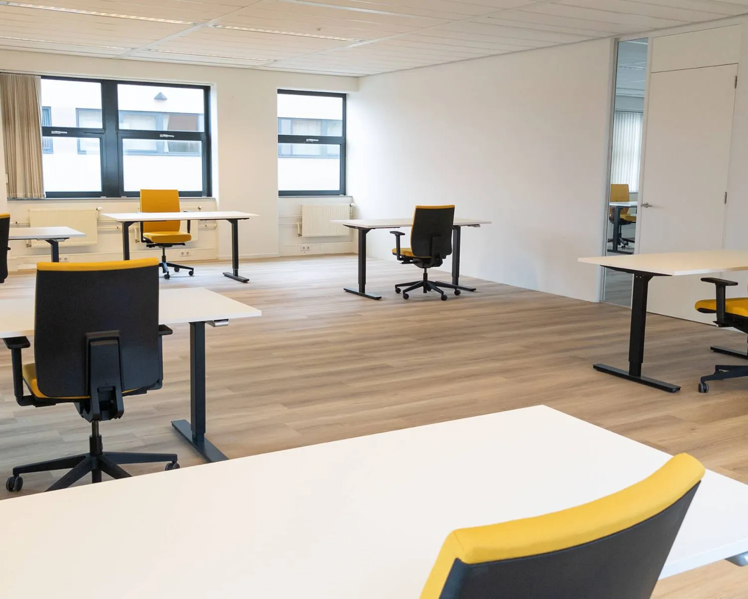 Moderne vergaderruimte in Utrecht met losse bureaus en geel-zwarte bureaustoelen.