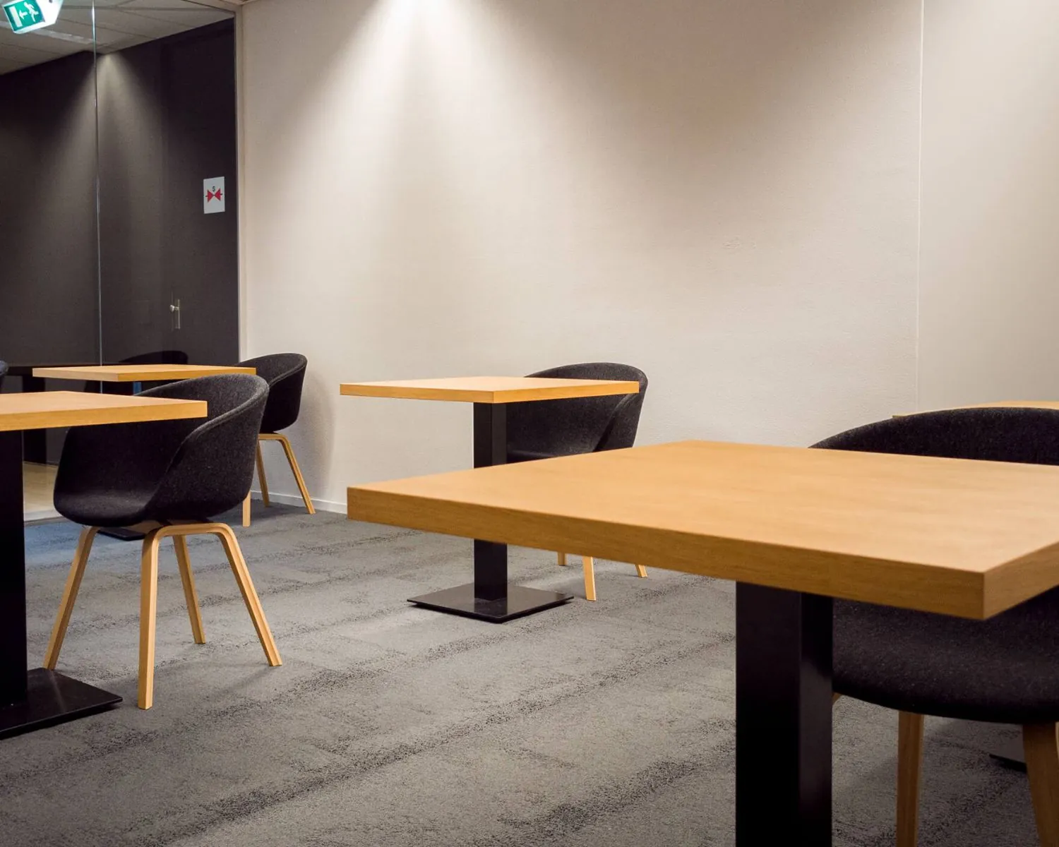 Moderne vergaderruimte in MyWorkshop Utrecht met houten tafels en zwarte stoelen.