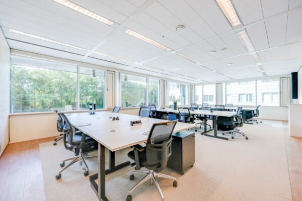 Lichte en ruime kantoorruimte met moderne bureaus en stoelen bij Tribes Amsterdam.