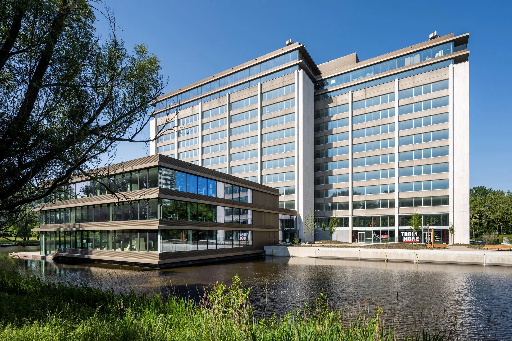 Modern kantoorgebouw aan de Nachtwachtlaan 20 met grote ramen en vijver op de voorgrond.