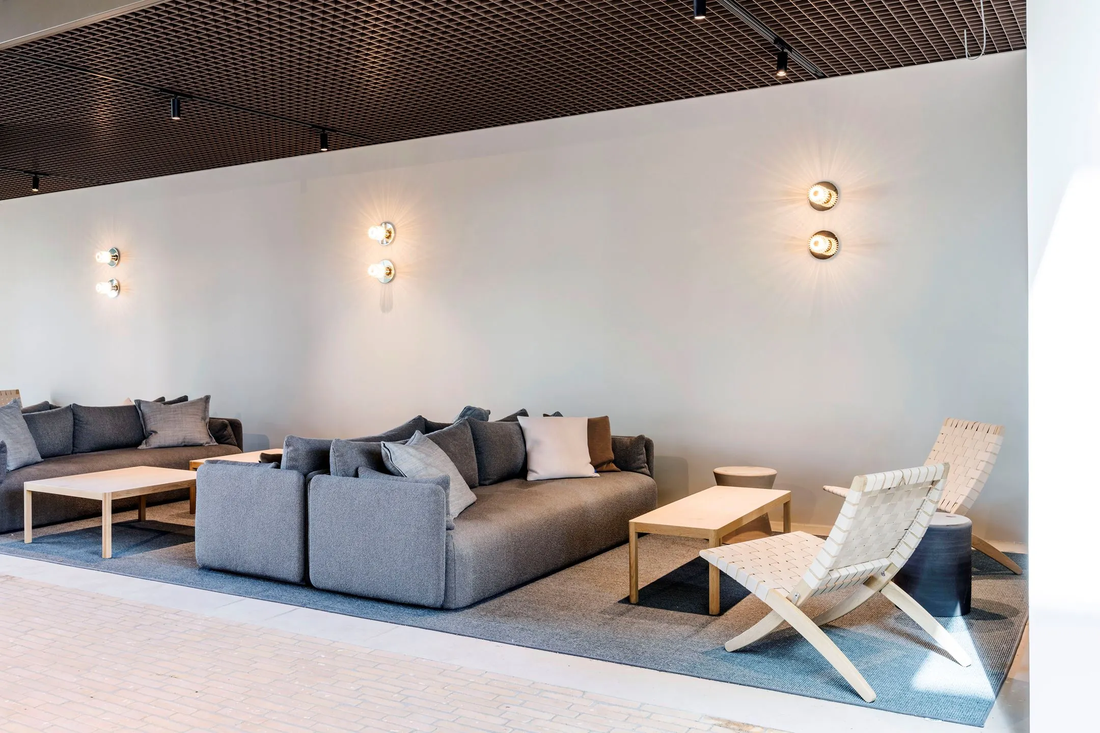 Moderne wachtruimte met grijze banken, houten tafels en designstoelen in Nachtwachtlaan 20.