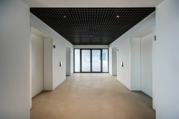 Moderne liftlobby met vier liften en glazen deuren bij Nachtwachtlaan 20.