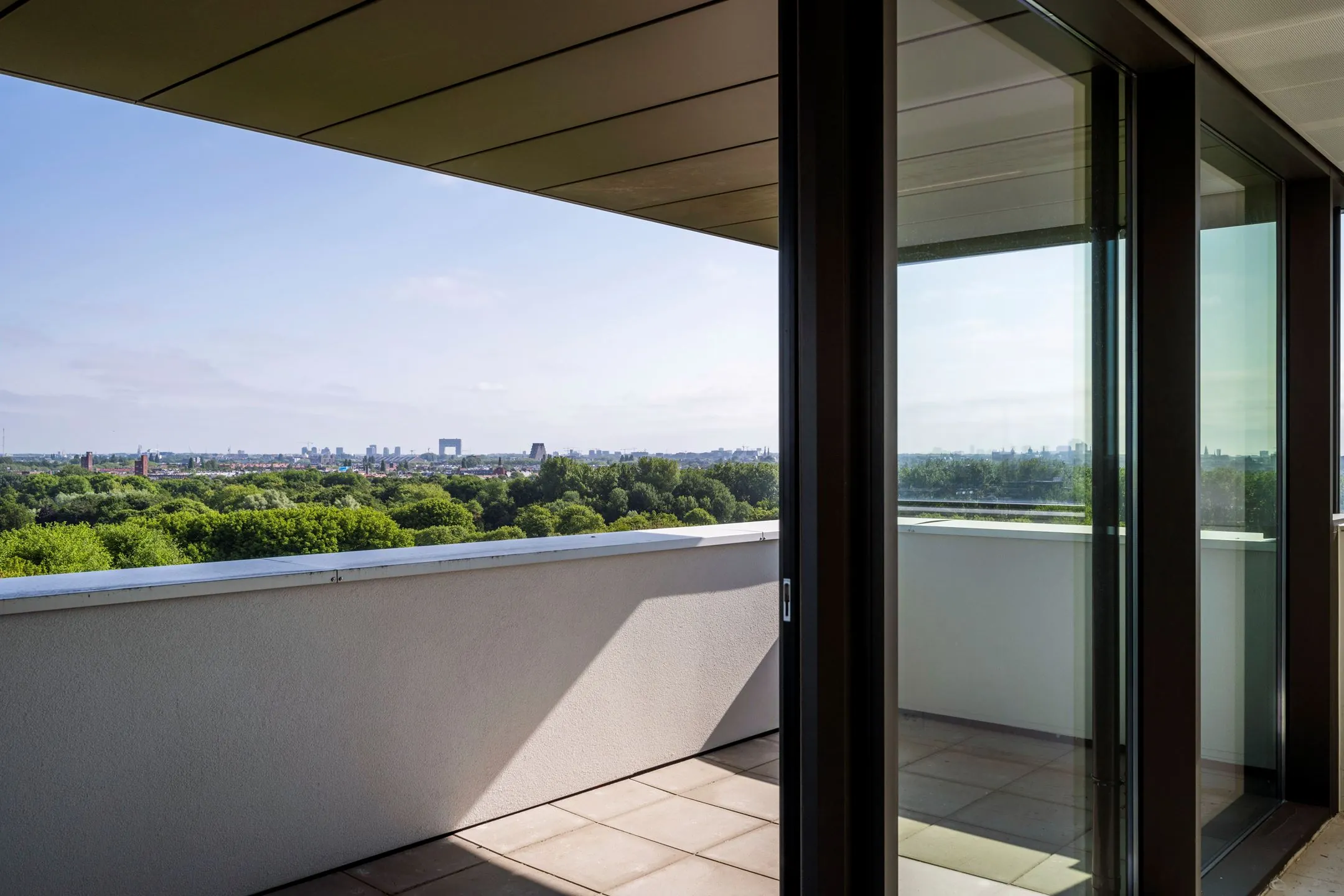 Uitzicht vanaf het balkon van Nachtwachtlaan 20 met panoramisch zicht over groen en de skyline van Amsterdam.