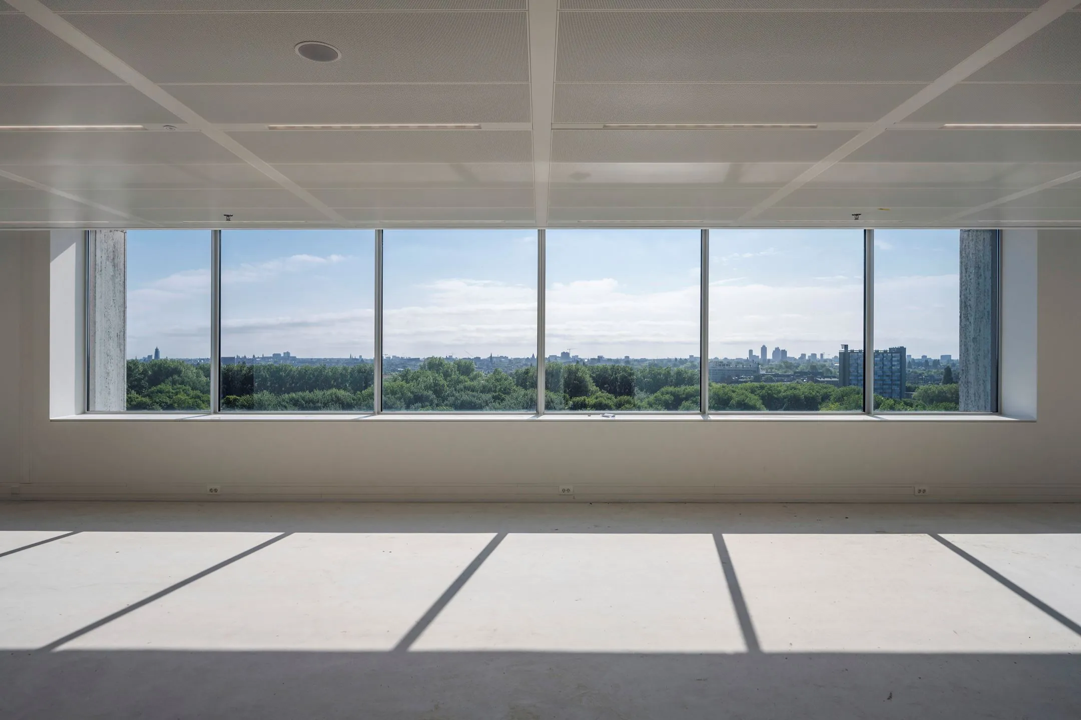Uitzicht op de skyline van Amsterdam vanuit een lege ruimte in het kantoorgebouw aan de Nachtwachtlaan 20.