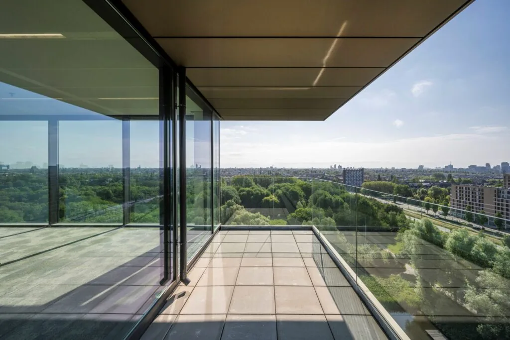 Uitstekend uitzicht vanaf een modern balkon met glazen balustrade aan de Nachtwachtlaan 20, met zicht op groen en stad.