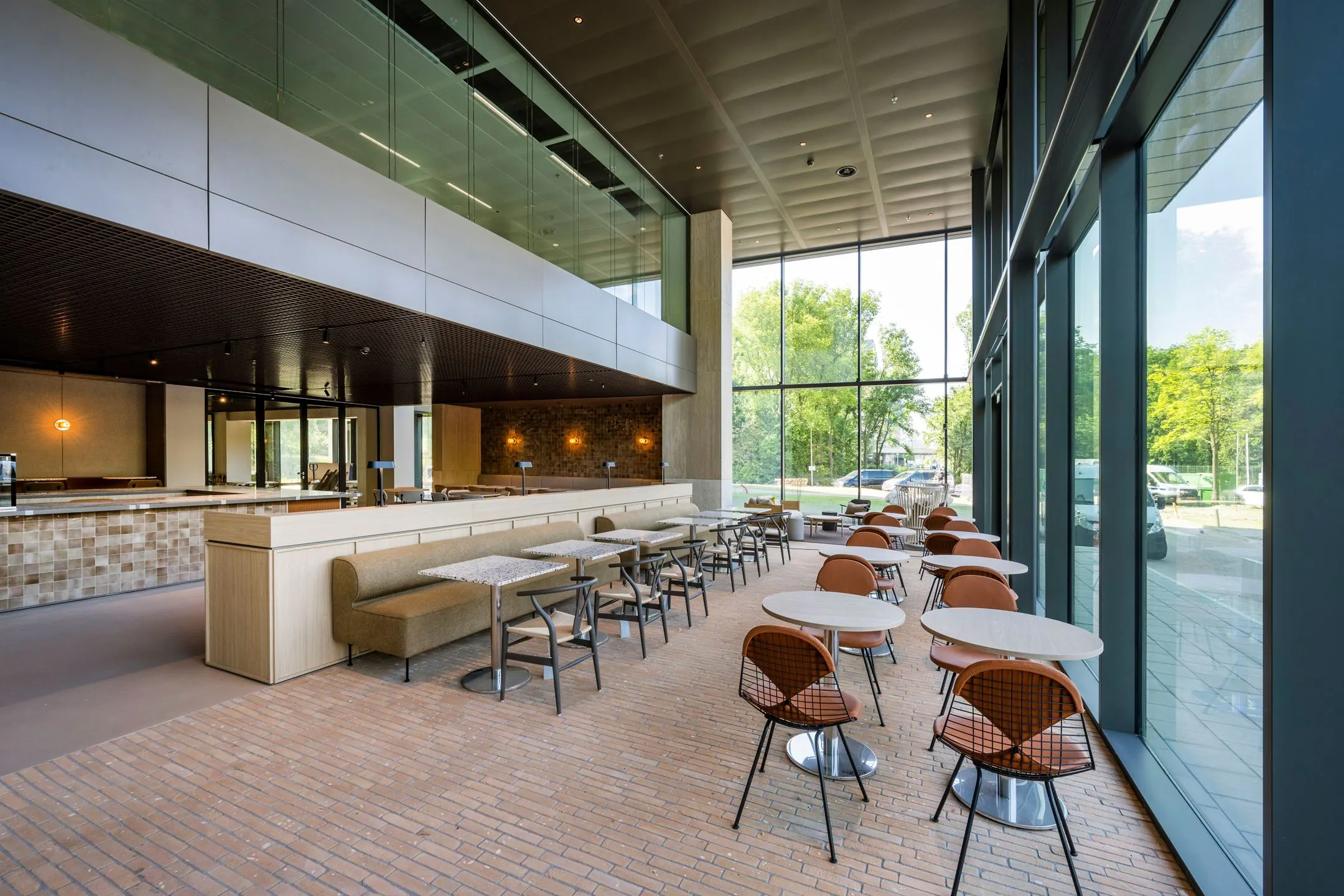 Moderne en lichte horecaruimte met zitplaatsen aan de Nachtwachtlaan 20, voorzien van grote raampartijen en eigentijds meubilair.