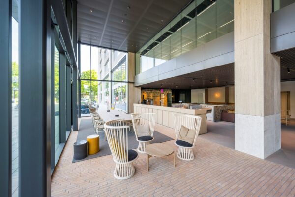 Moderne ontvangst- of lobbyruimte op Nachtwachtlaan 20 met hoge raampartijen, houten meubilair en een open indeling.