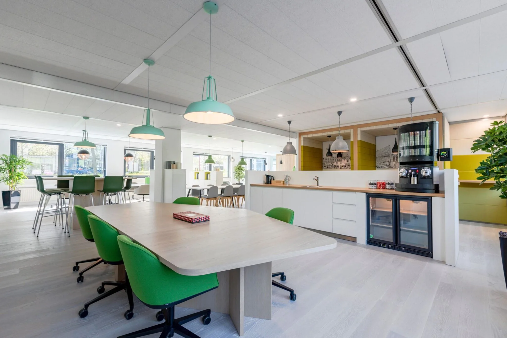 Moderne, open kantoorruimte in Nevelgaarde 8 met groene stoelen, een koffiecorner en veel natuurlijk licht.