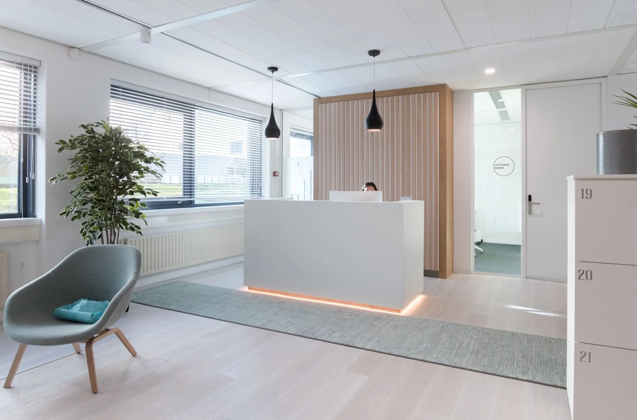 Moderne en lichte receptieruimte in kantoorpand Nevelgaarde 8 met balie, zitstoel en kantoorruimte op de achtergrond.