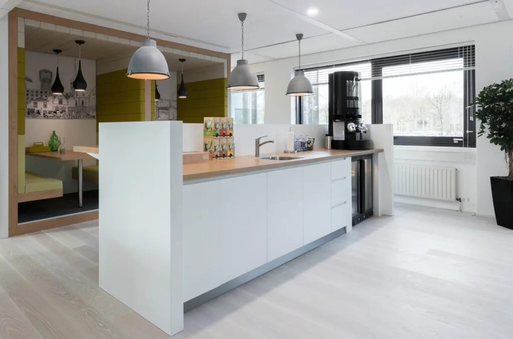 Moderne kantoorkeuken bij Nevelgaarde 8 met witte kasten, houten werkblad en koffiehoek.