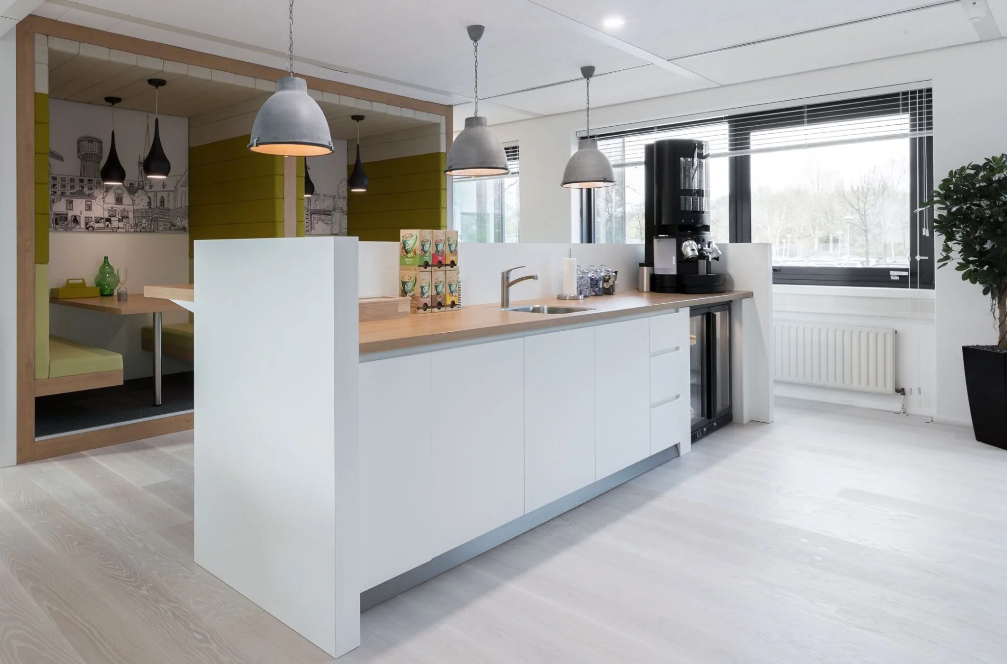 Moderne kantoorkeuken bij Nevelgaarde 8 met witte kasten, houten werkblad en koffiehoek.