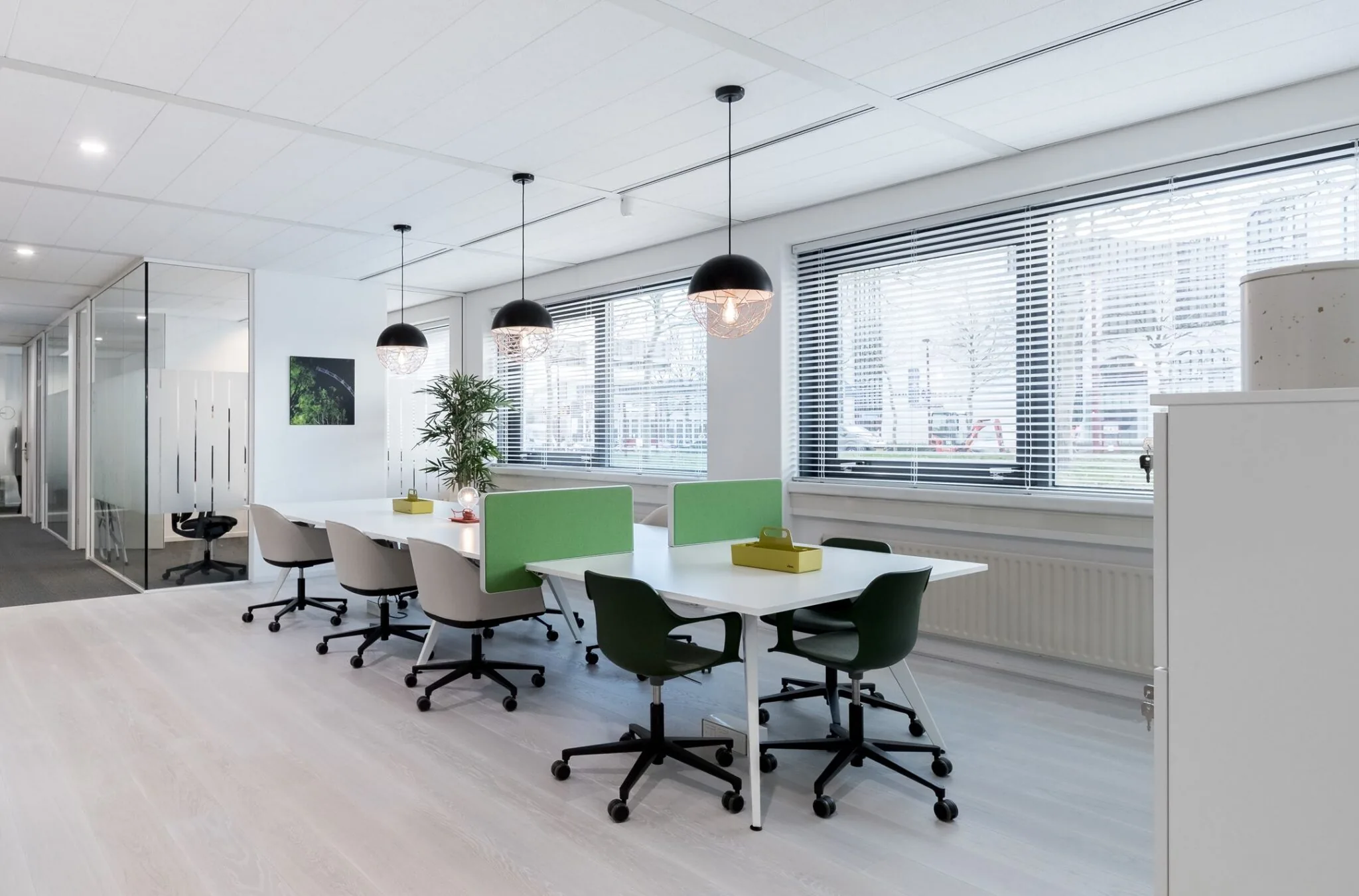 Moderne, lichte kantoortuin met werkplekken, bureaustoelen en groene schermen bij Nevelgaarde 8.