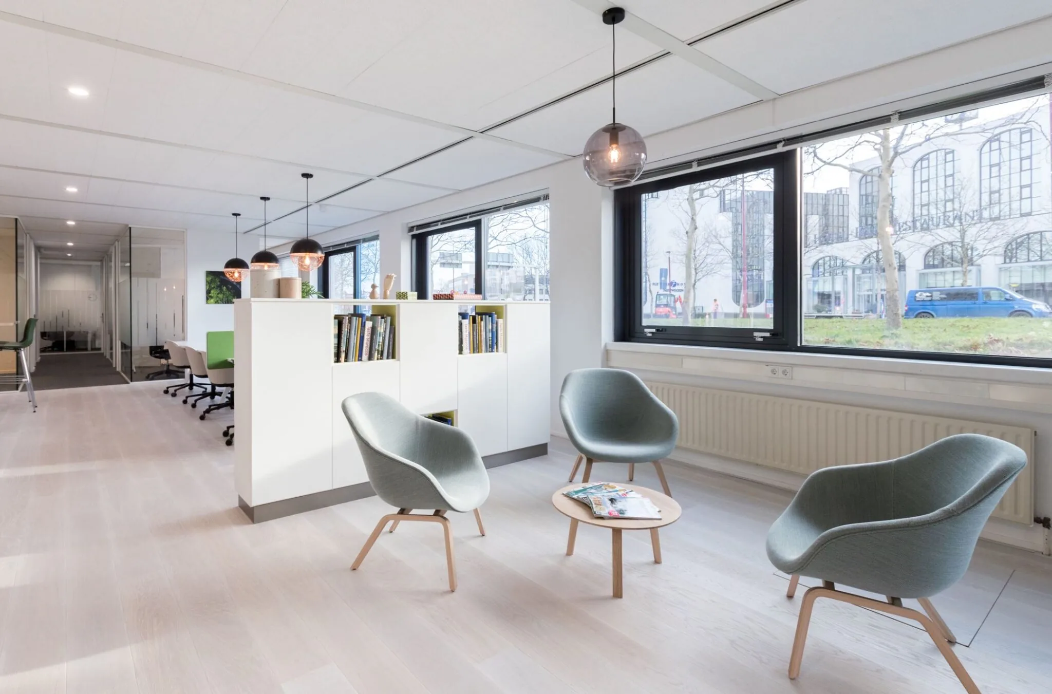 Moderne en lichte kantoorruimte aan Nevelgaarde 8 met een zithoek, boekenkast en grote ramen met uitzicht op de straat.