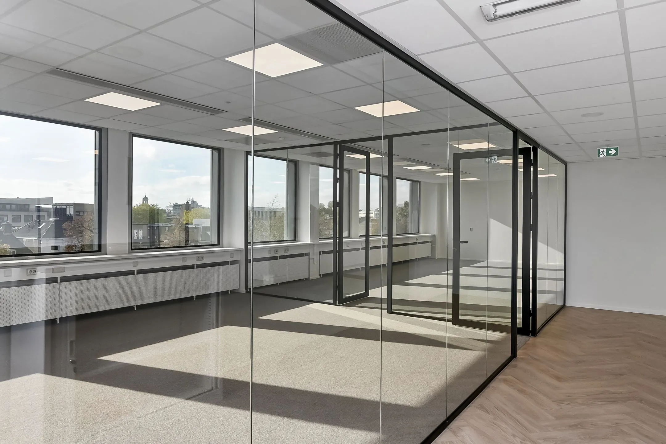 Licht en modern kantoorpand in Arnhem met glazen vergaderruimtes en grote ramen.