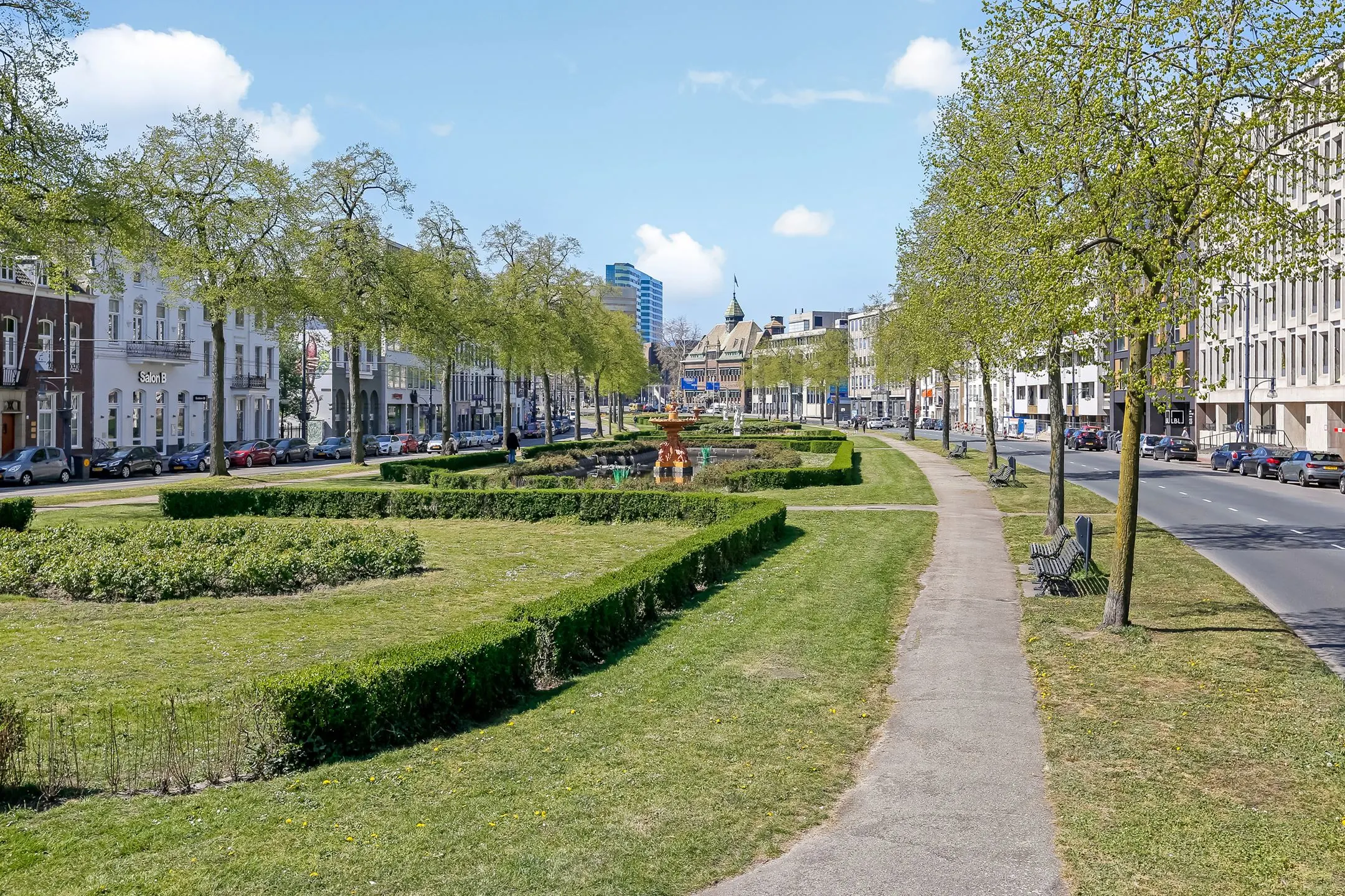 Groene stadsboulevard in Arnhem met een centrale fontein, gescheiden rijbanen en historische gebouwen aan weerszijden.