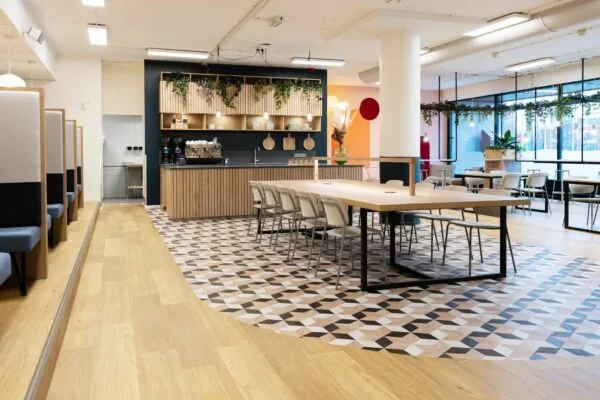 Moderne en sfeervolle kantoorruimte van Newday Arnhem met een koffiebar, lange vergadertafel en zitplekken.