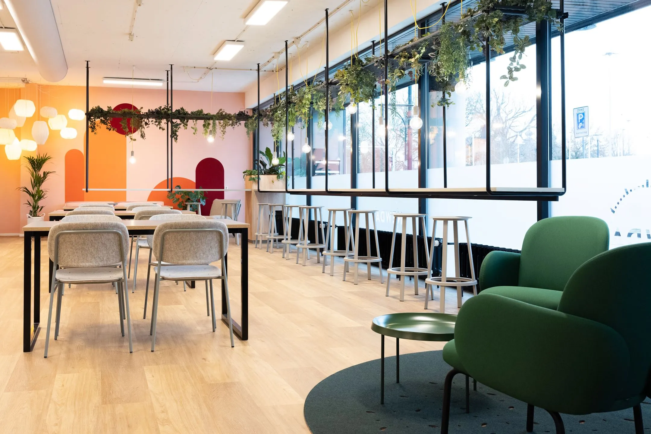 Moderne en kleurrijke kantoorruimte bij Newday Arnhem met zitgedeelte, lange werktafels en hangende planten.