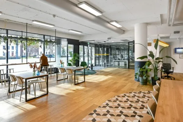 Moderne en lichte kantoorlobby van Newday Arnhem met houten vloer, zitplekken en grote ramen aan de straatzijde.