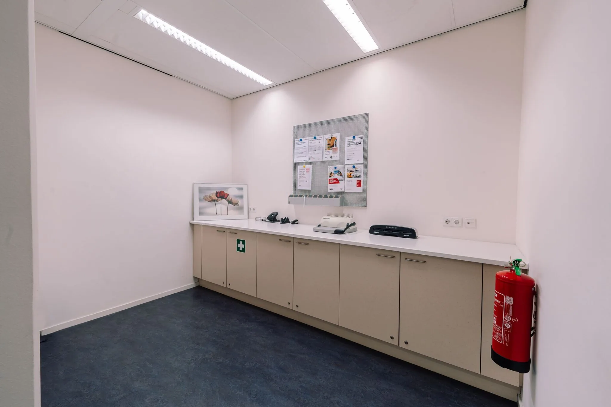Kopieerruimte in kantoorpand Newtonlaan 115 met kasten, printer, telefoon en brandblusser aan de muur.