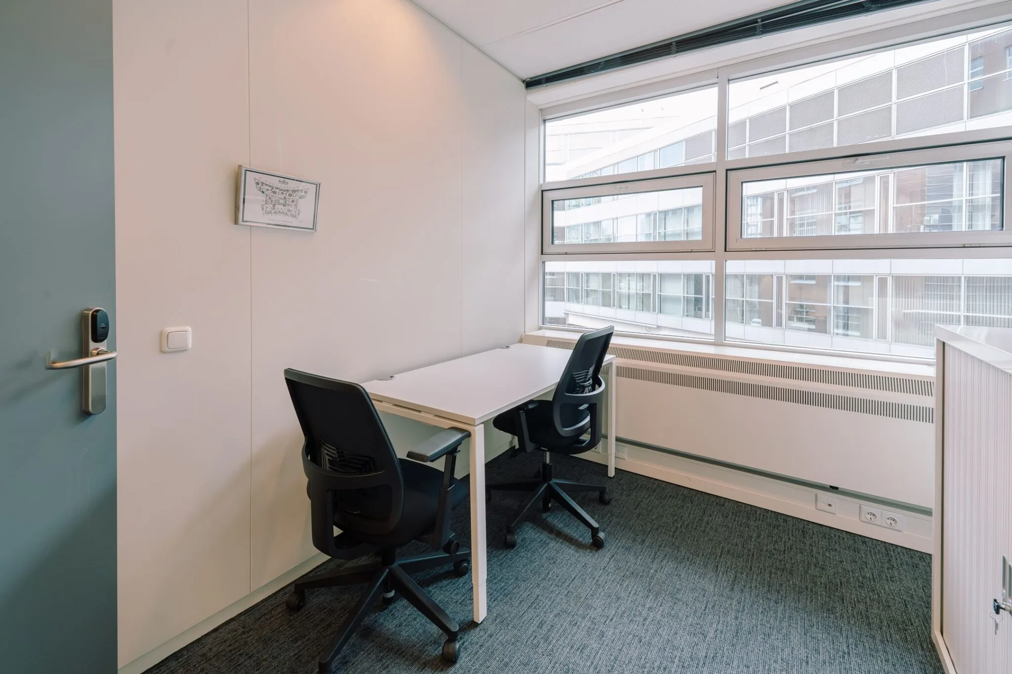 Kleine, moderne kantoorruimte aan de Newtonlaan 115 met twee bureaustoelen en een groot raam met uitzicht op naastgelegen gebouwen.