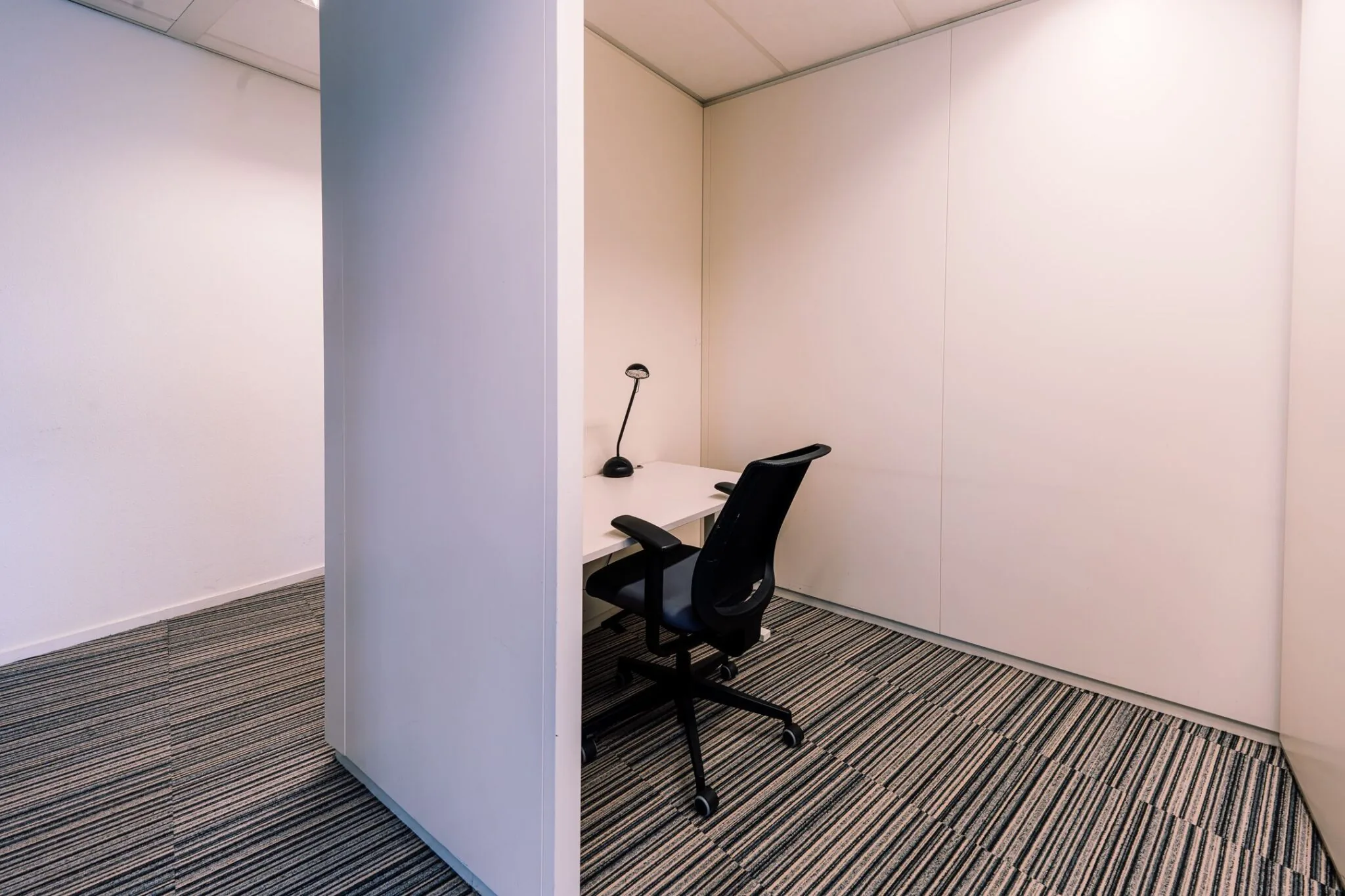 Kleine kantoorruimte met een bureau, bureaustoel en bureaulamp in Newtonlaan 115.