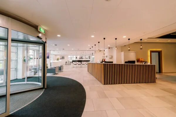 Moderne en ruime entreehal van Newtonlaan 115 met balie, zitgedeelte en hanglampen.