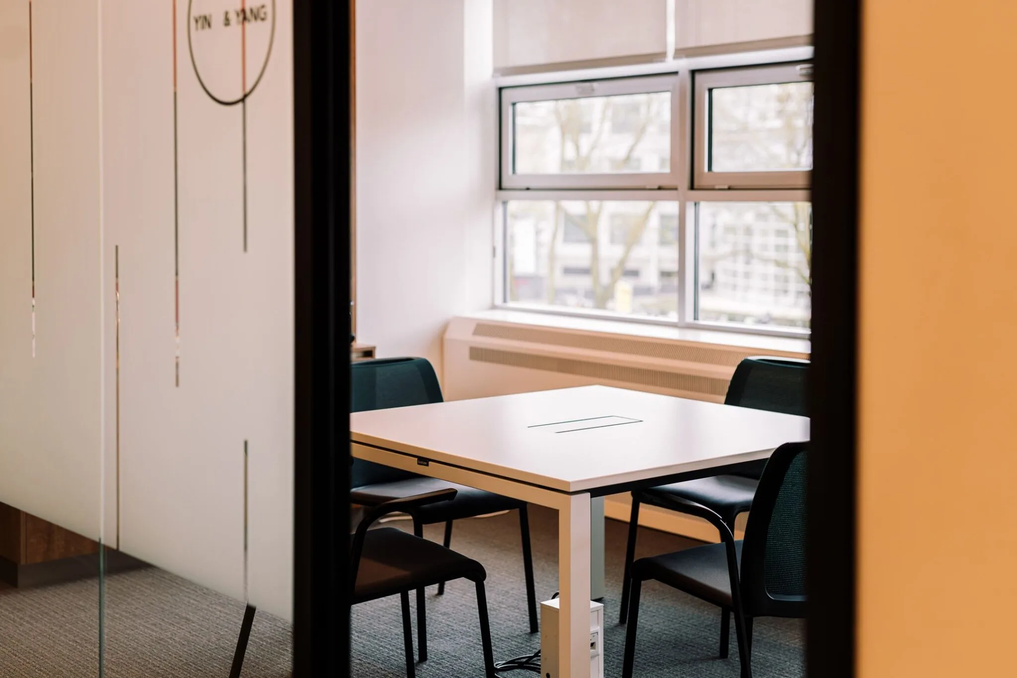 Vergaderruimte met vier stoelen en een tafel bij het raam in Newtonlaan 115.