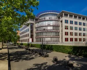 Kantoorgebouw aan de Newtonlaan in Utrecht met moderne gevel en rode raamkozijnen op een zonnige dag.