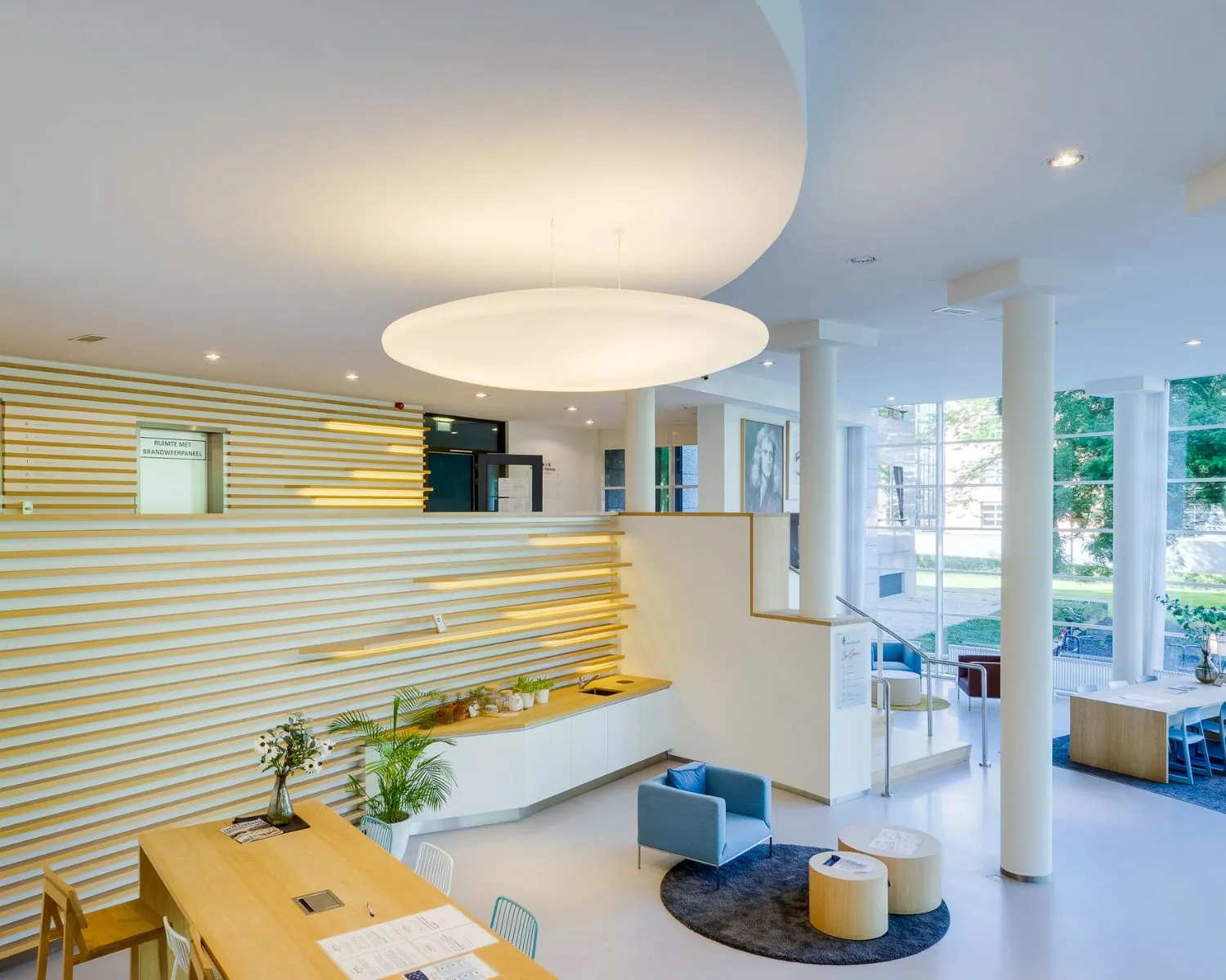 Moderne en licht ingerichte ontvangstruimte in het kantoorpand aan de Newtonlaan 51-97 met zithoeken en houten details.