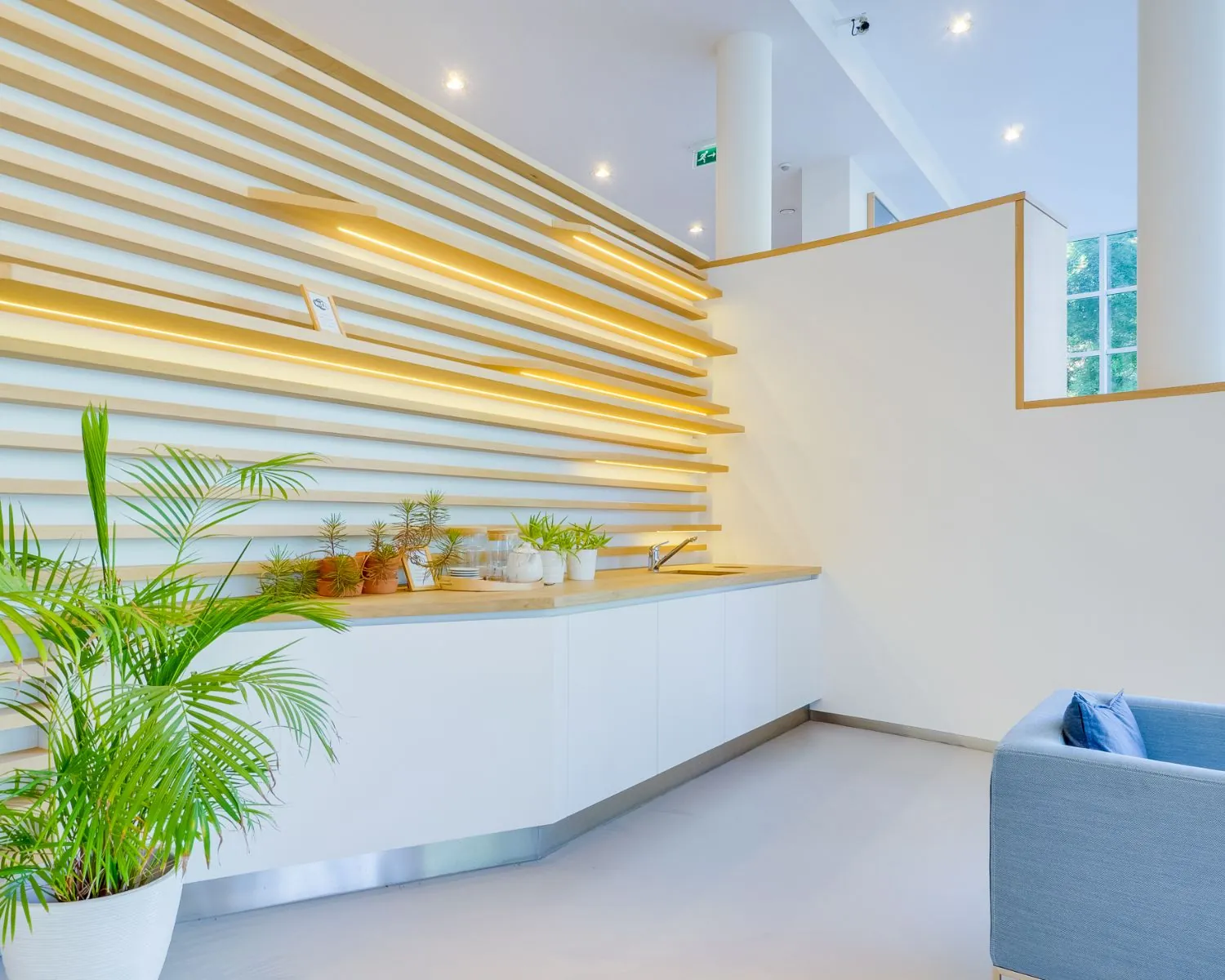 Moderne pantry met houten accenten en ingebouwde verlichting in een strak wit interieur aan de Newtonlaan.