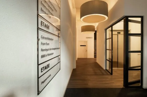 Moderne entreehal van kantoorpand aan de Nieuwe Binnenweg 77 E met lift, trap en bord met bedrijfsnamen.