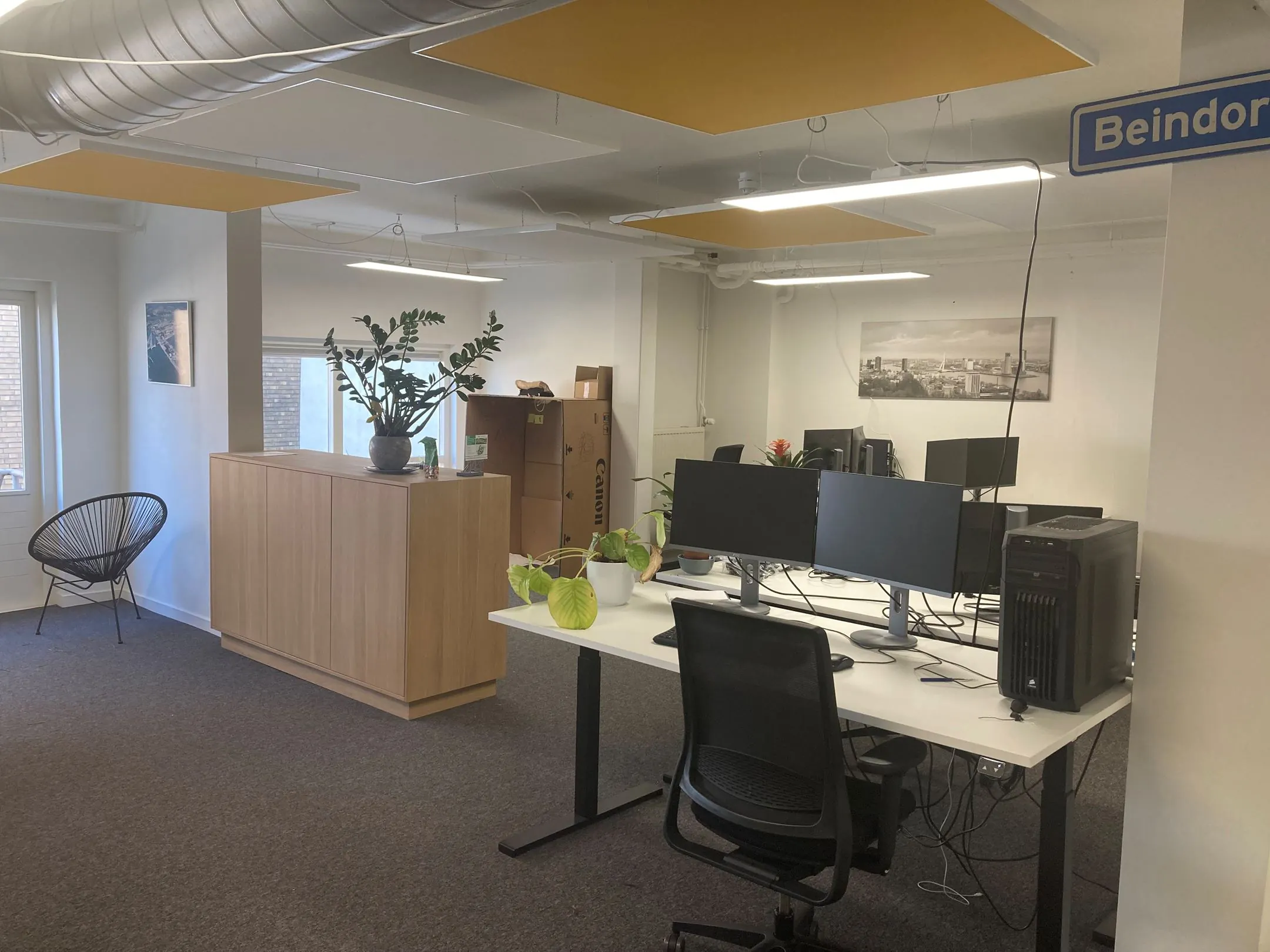 Moderne kantoorruimte aan de Nieuwe Binnenweg 77 E met bureaus, computerschermen, planten en decoratieve elementen.