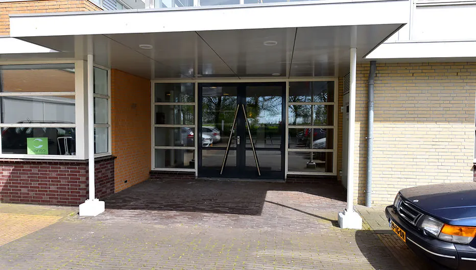 Entree van een modern gebouw aan de Oude Vaartweg 2 met overkapping en geparkeerde auto.