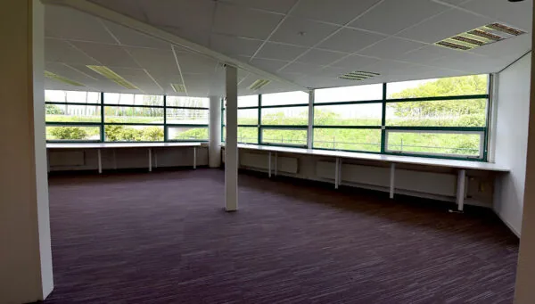 Lege kantoorruimte met grote ramen en uitzicht op groen, gelegen aan de Oude Vaartweg 2.