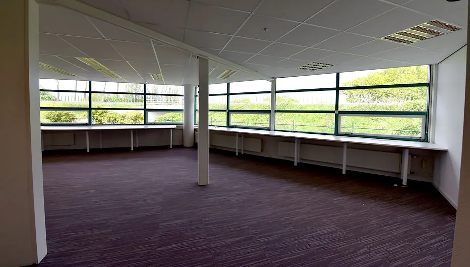 Lege kantoorruimte met grote ramen en uitzicht op groen, gelegen aan de Oude Vaartweg 2.