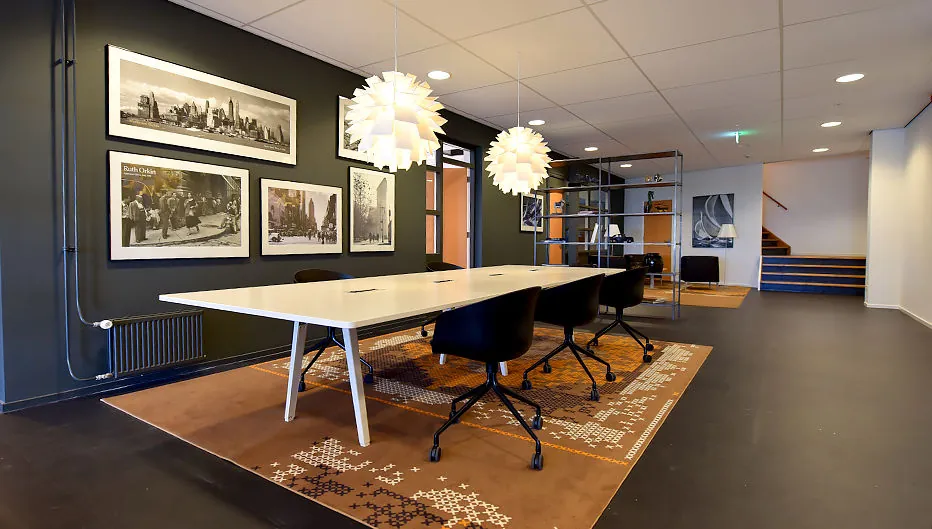 Moderne vergaderruimte aan de Oude Vaartweg 2 met lange tafel, designlampen, wandfoto’s en open kast.