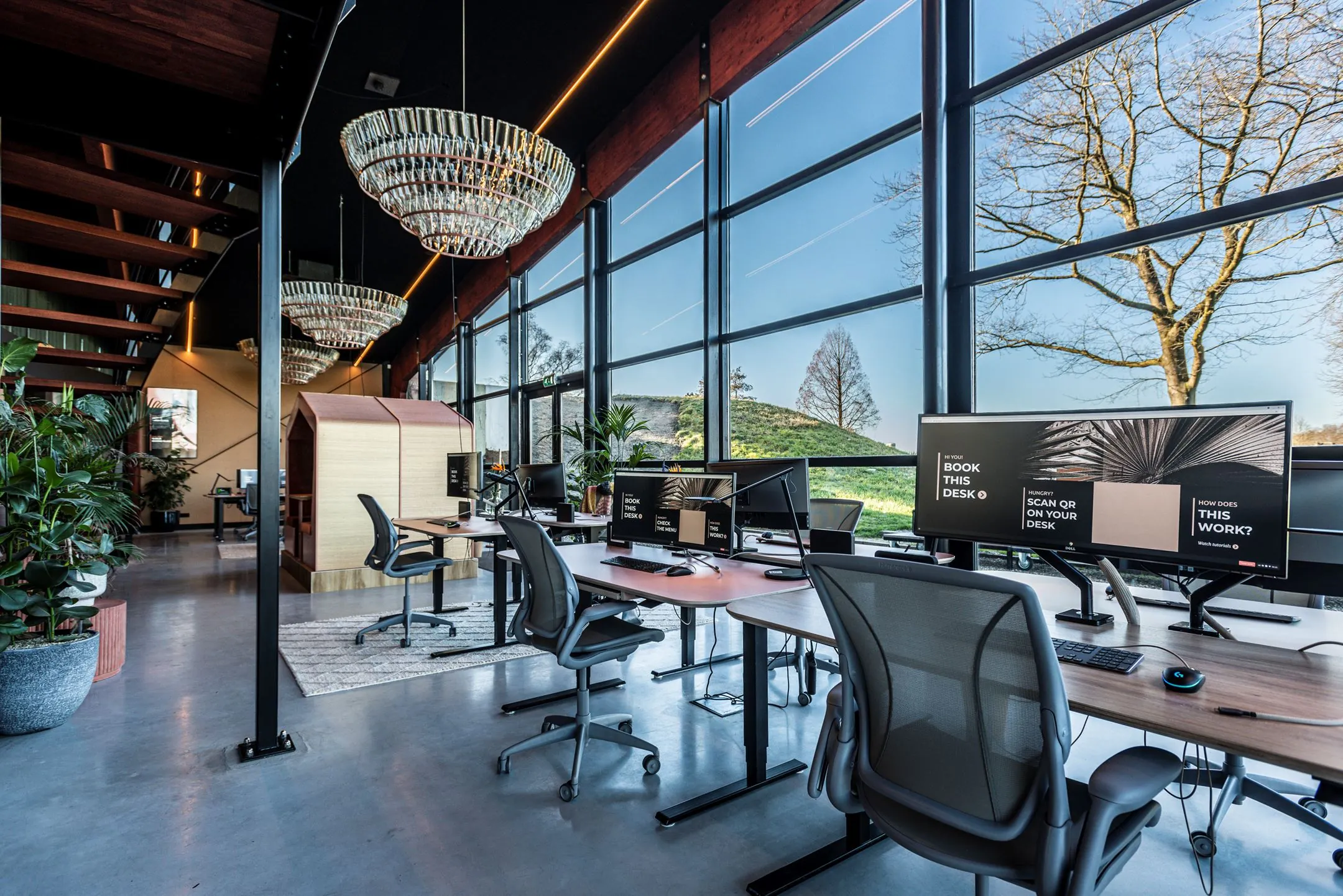 Modern ingericht kantoor aan de Oudhuizerstraat 31 met grote ramen, werkplekken, planten en opvallende kroonluchters.