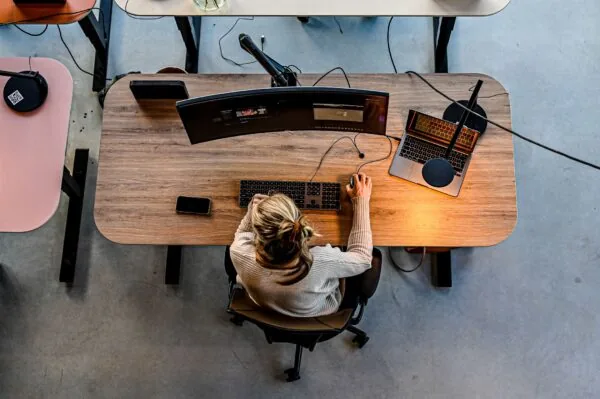 Vrouw werkt aan een bureau op Oudhuizerstraat 31 met een groot gebogen beeldscherm en een laptop.