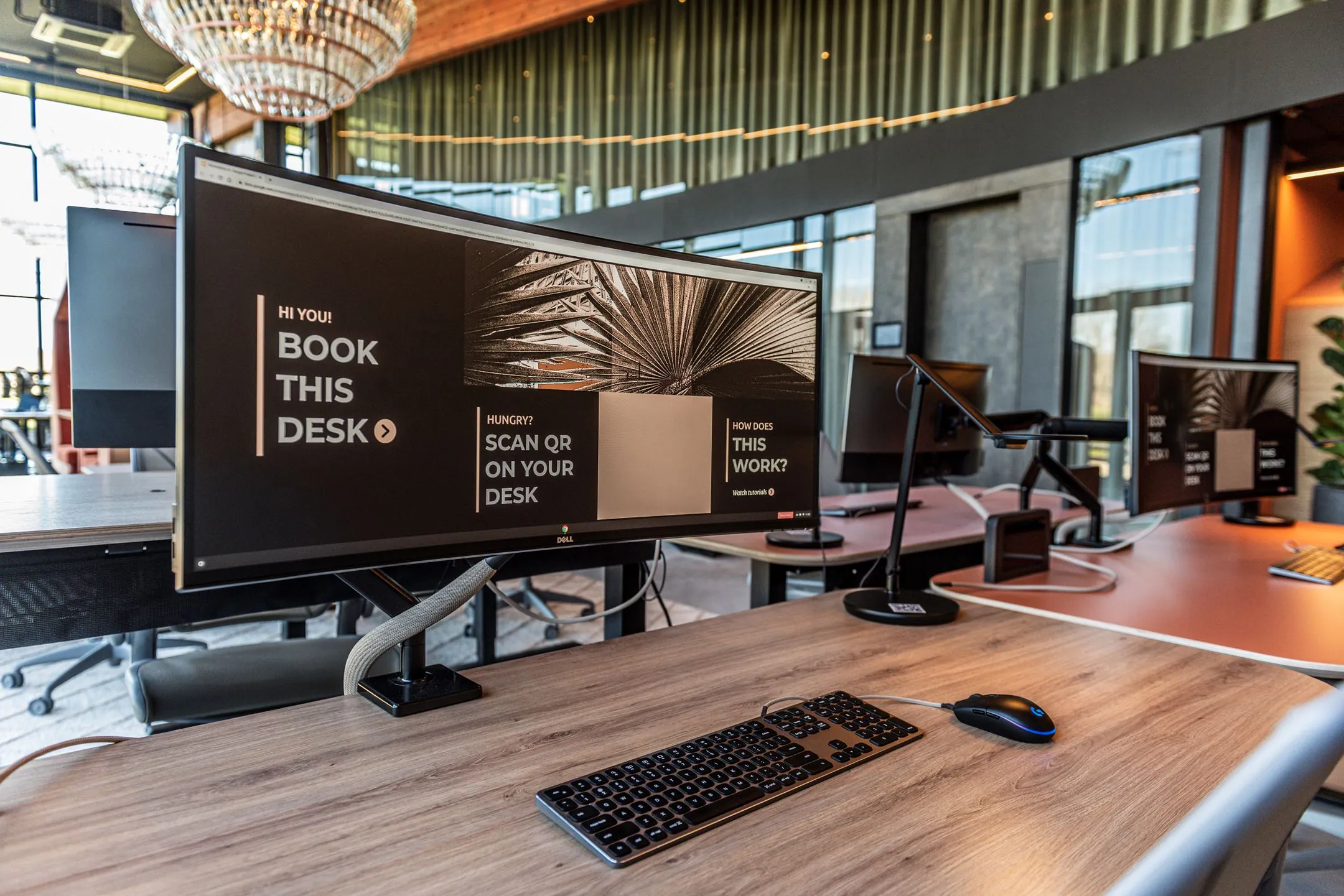 Modern flexibel kantoor met werkplekken met beeldschermen waarop staat "Book this desk" op Oudhuizerstraat 31.