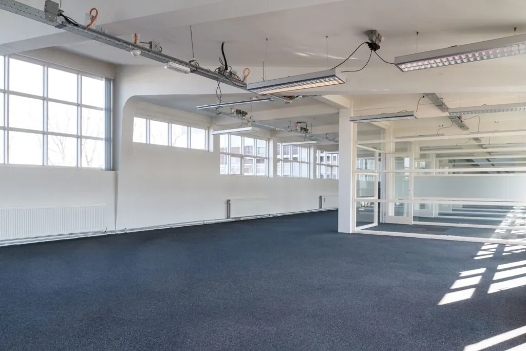 Licht en ruim leegstaand kantoorinterieur aan de Overschieseweg 35 met grote ramen en systeemplafondverlichting.