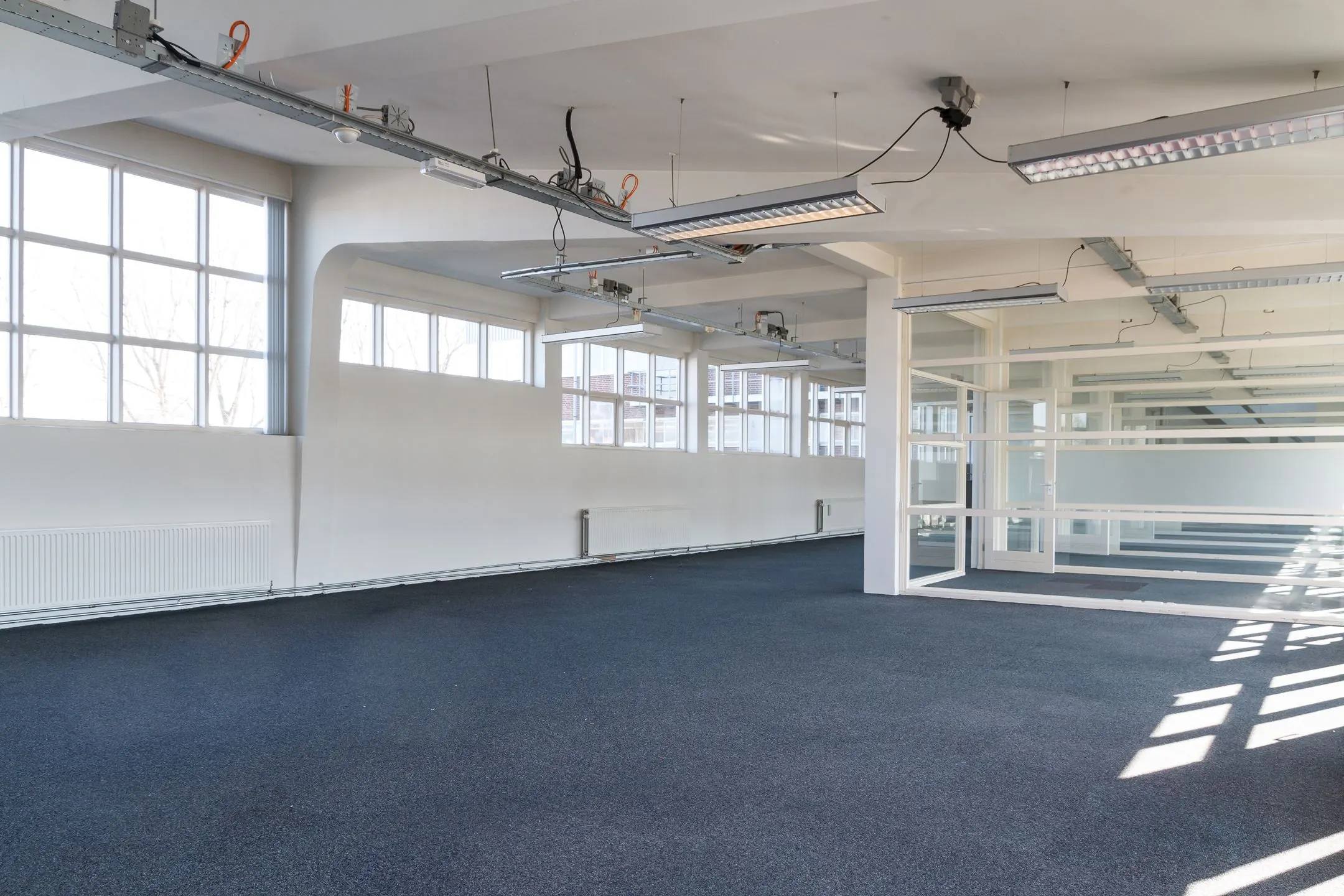 Licht en ruim leegstaand kantoorinterieur aan de Overschieseweg 35 met grote ramen en systeemplafondverlichting.