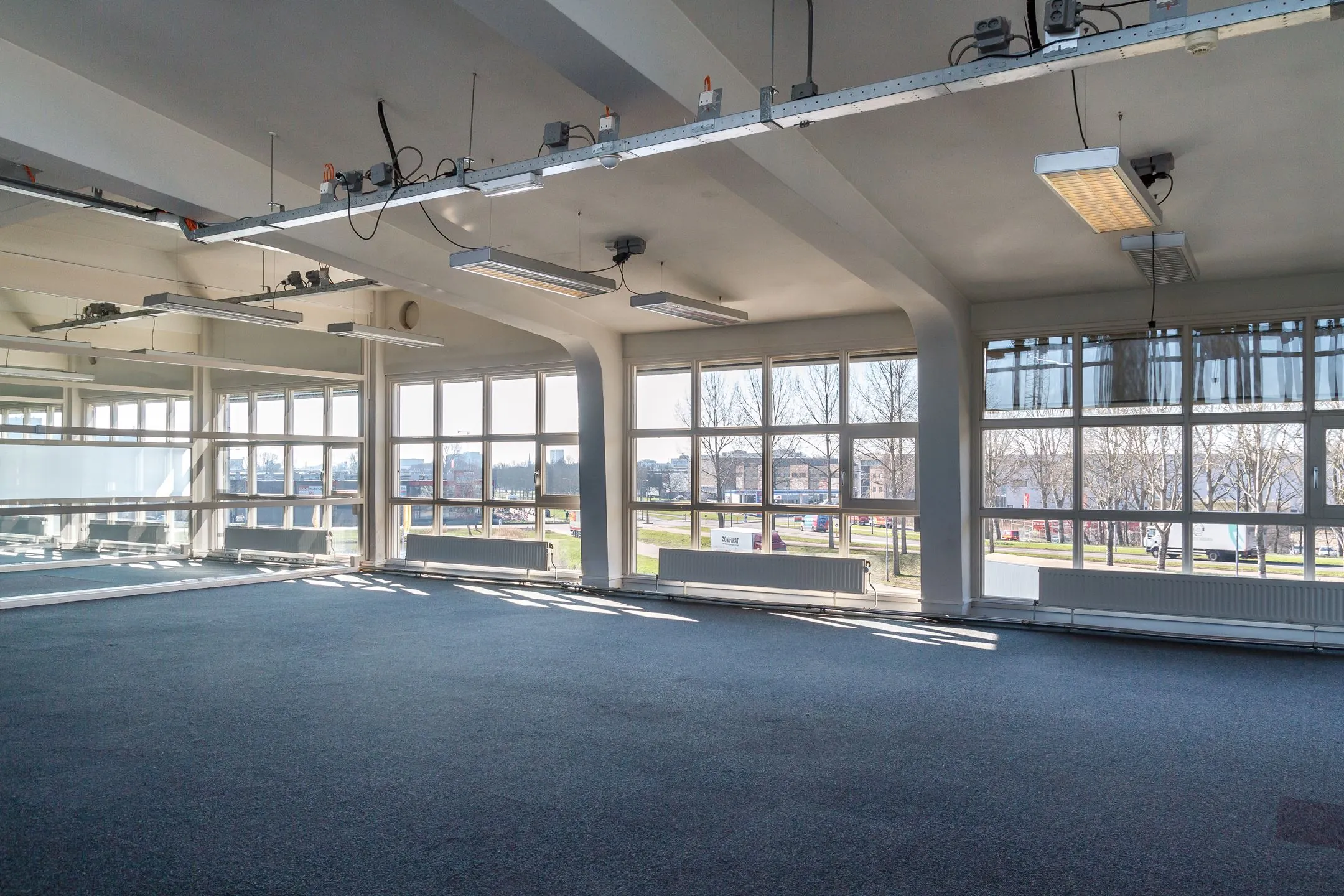 Lichte, leegstaande kantoorruimte aan de Overschieseweg 35 met grote ramen en uitzicht op een bedrijventerrein.