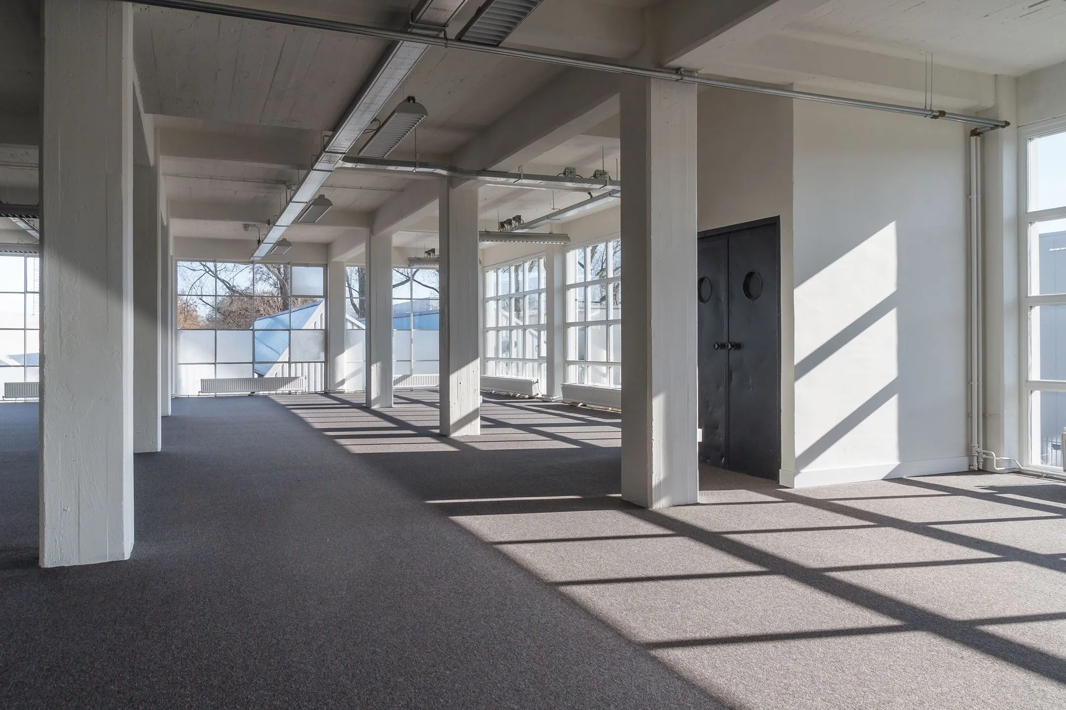 Lichte, lege kantoorruimte aan de Overschieseweg 35 met grote ramen en betonnen kolommen.