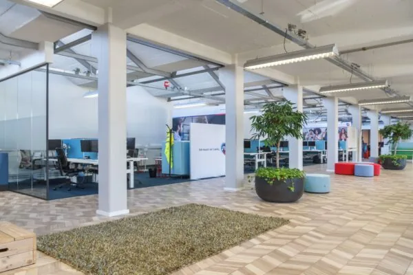 Moderne en open kantoorruimte aan de Overschieseweg 35 met werkplekken, planten en zitbanken.