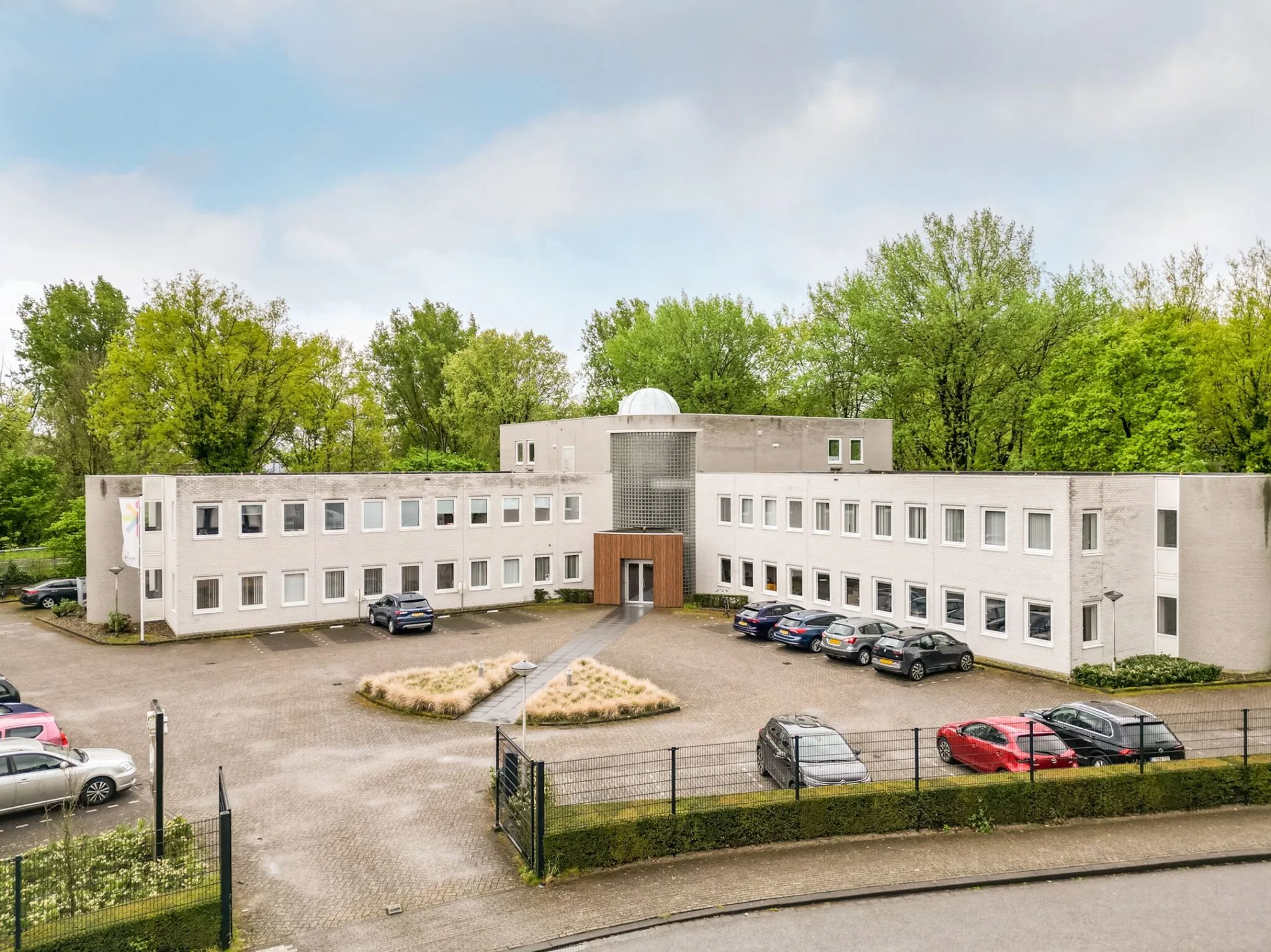 Modern kantoorgebouw aan de Paardeweide 2A-4C met parkeerplaatsen en omringd door groen.