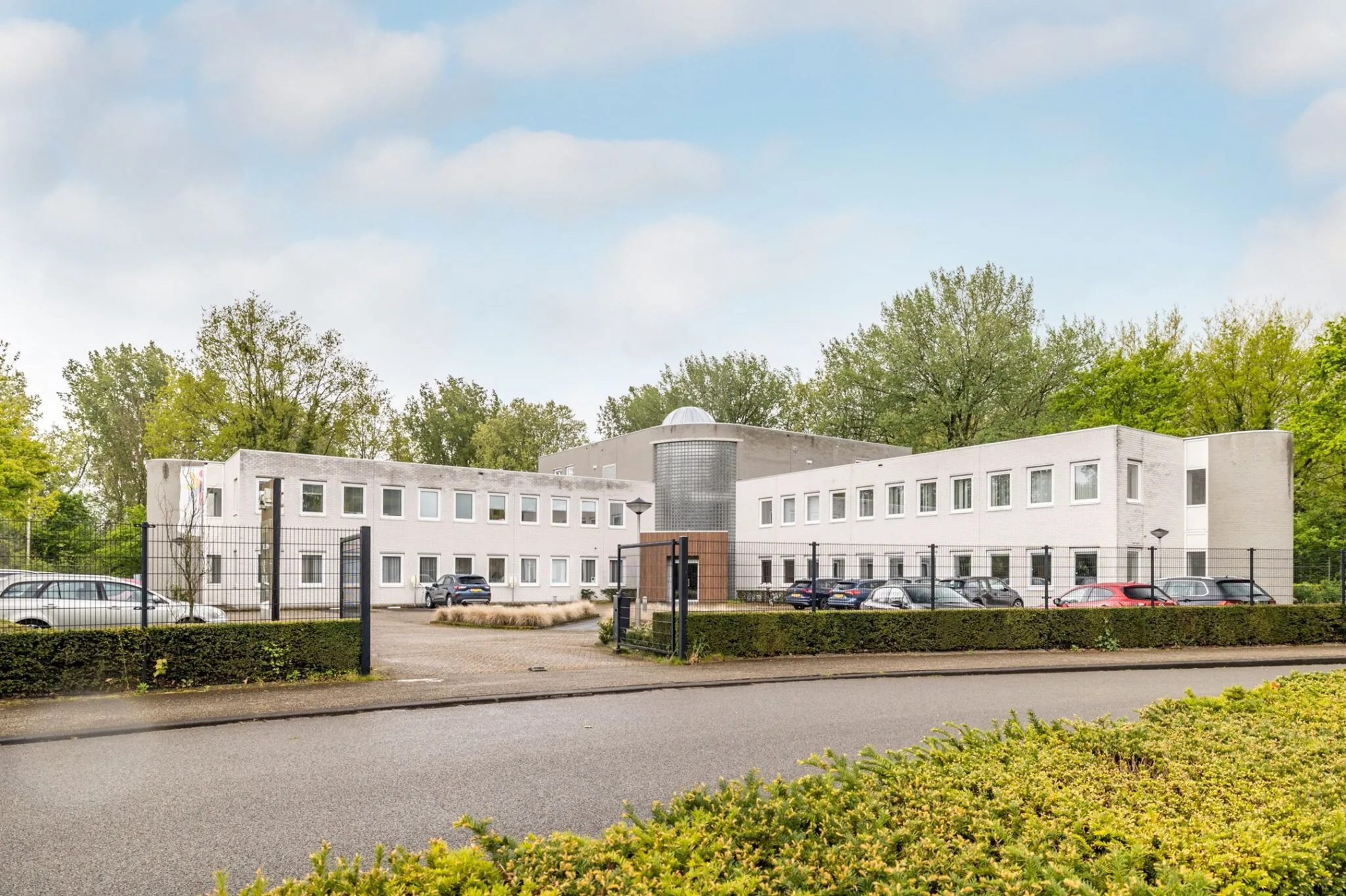 Vooraanzicht van het kantoorpand aan Paardeweide 2A-4C met parkeergelegenheid en omheining.