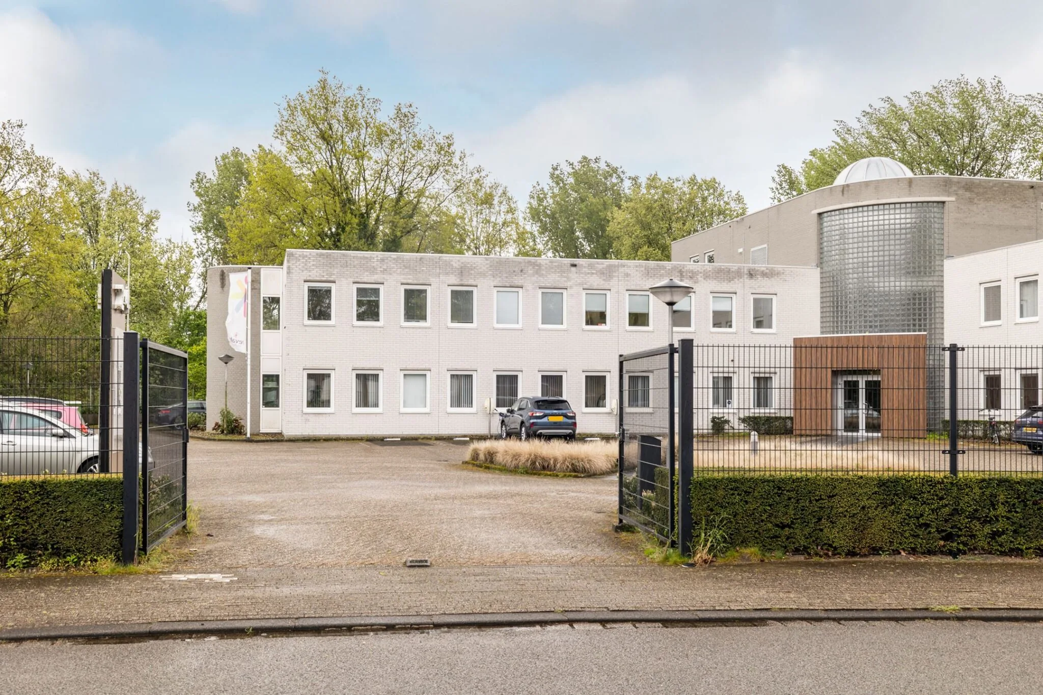 Vooraanzicht van een modern kantoorpand aan de Paardeweide 2A-4C met parkeergelegenheid en hekwerk.