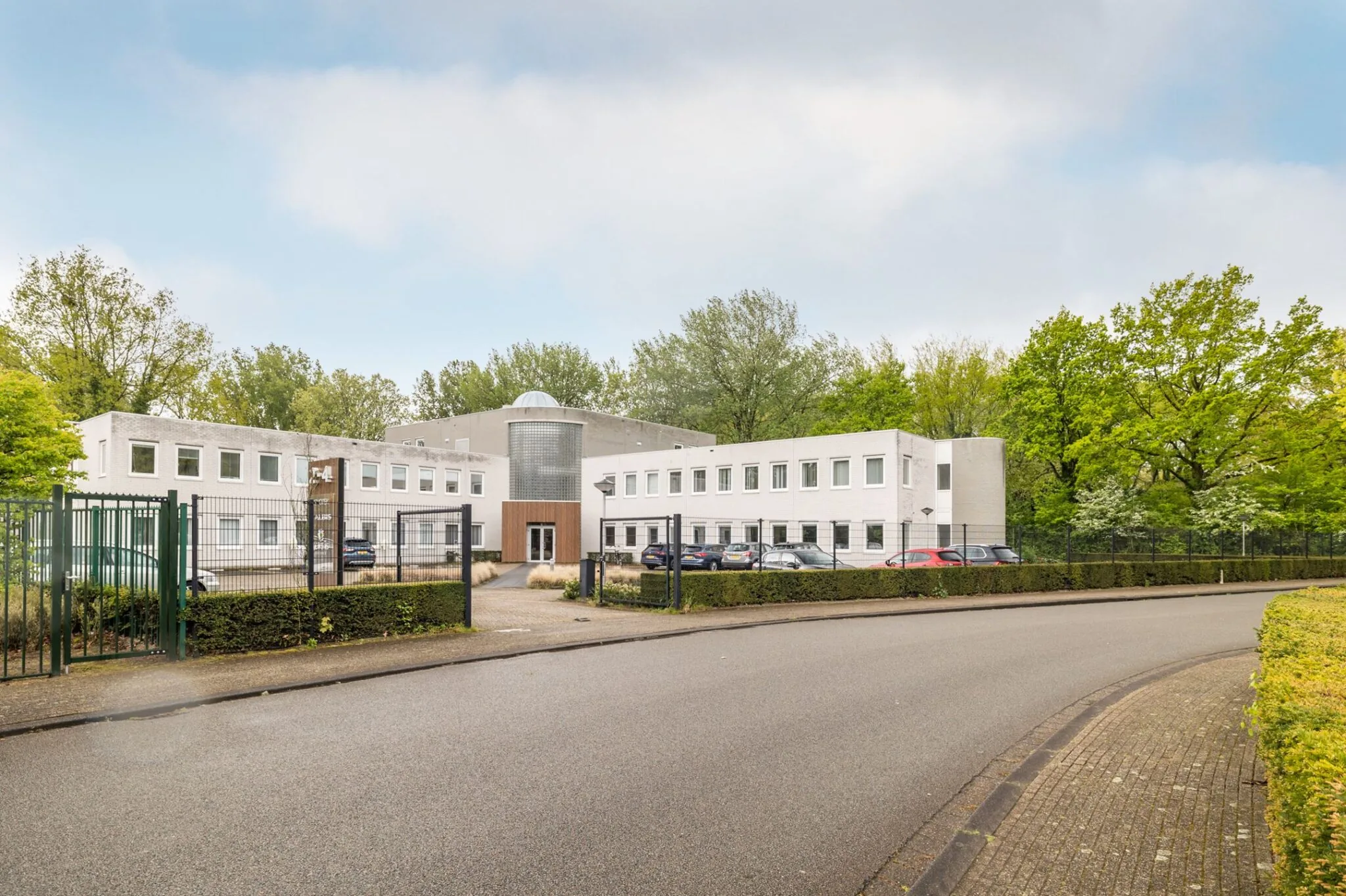 Wit kantoorgebouw aan de Paardeweide met parkeervakken aan de voorzijde en omringd door groen.
