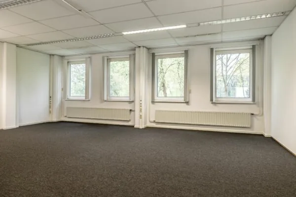 Lichte, lege kantoorruimte met vier ramen, systeemplafond en donkergrijze vloerbedekking in Paardeweide 2A-4C.
